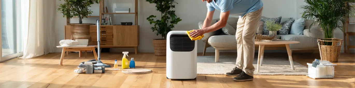 Personne nettoyant un climatiseur mobile silencieux en 7 étapes simples avec des produits d'entretien écologiques