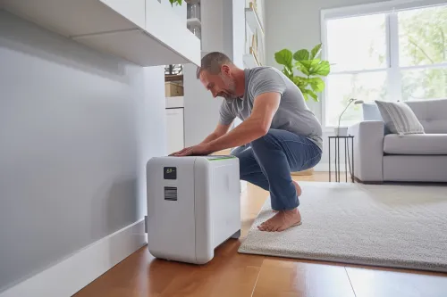 Climatiseur mobile positionné près d'une fenêtre avec kit d'évacuation installé correctement pour un fonctionnement silencieux